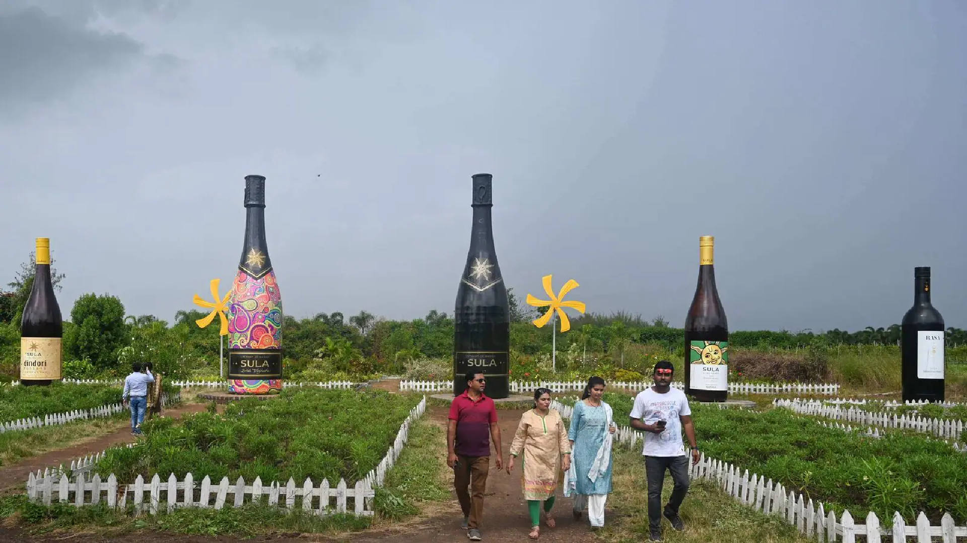 Visitors walk past giant sized wine bottles during a winery tour and wine tasting session at the Sula Vineyards in Nashik